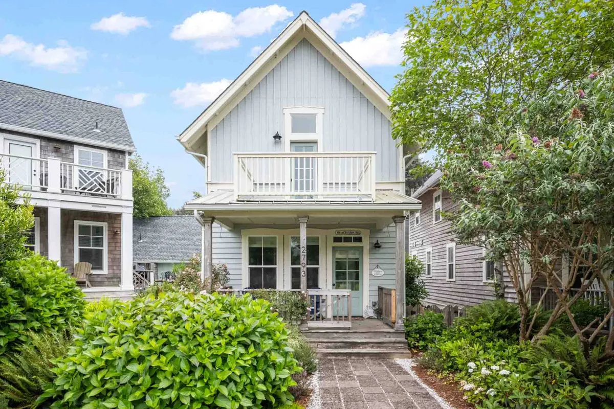 An inviting front porch is framed by greenery and blue siding, with a balcony above. The image conveys a welcoming entrance and hints at the social, communal spirit of the neighborhood—ideal for gathering before heading to shared amenities like the pool or playground.