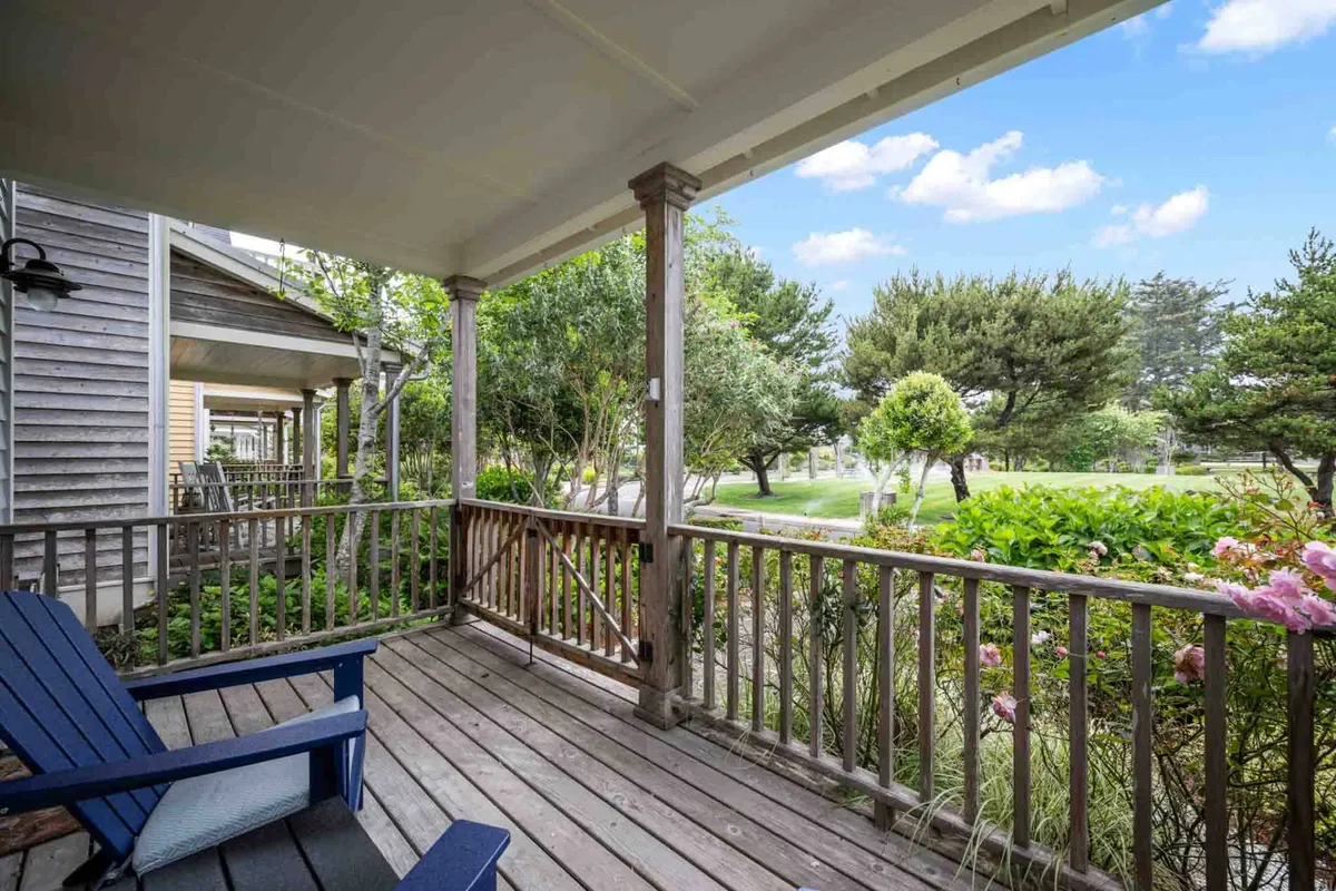 The exterior view features a wooden deck with blue chairs surrounded by lush greenery and blooming garden flowers. The setting is peaceful and ideal for relaxing, socializing, or enjoying morning coffee—mirroring the resort atmosphere that blends private tranquility with shared enjoyment.